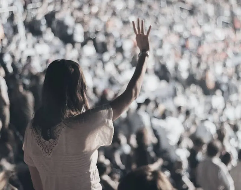 A woman raising her hand in a large crowd